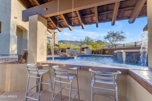 view of swimming pool with a mountain view, pool water feature, and an outdoor bar