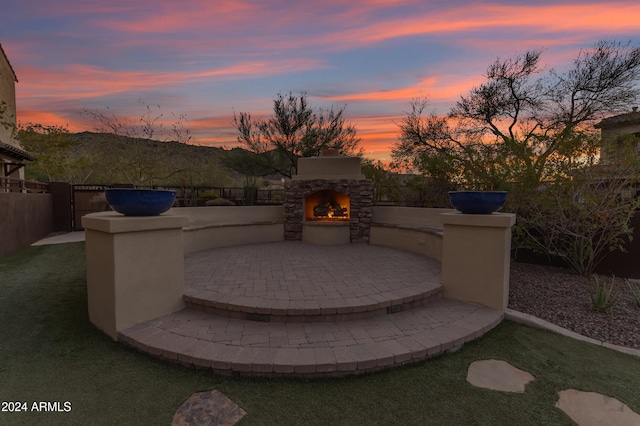 patio terrace at dusk with an outdoor stone fireplace