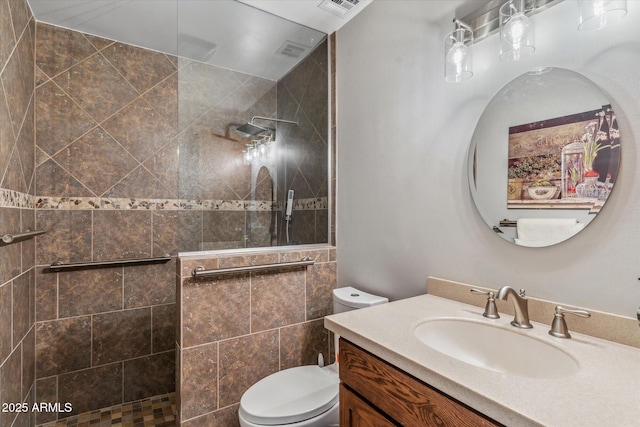 bathroom with vanity, a tile shower, and toilet