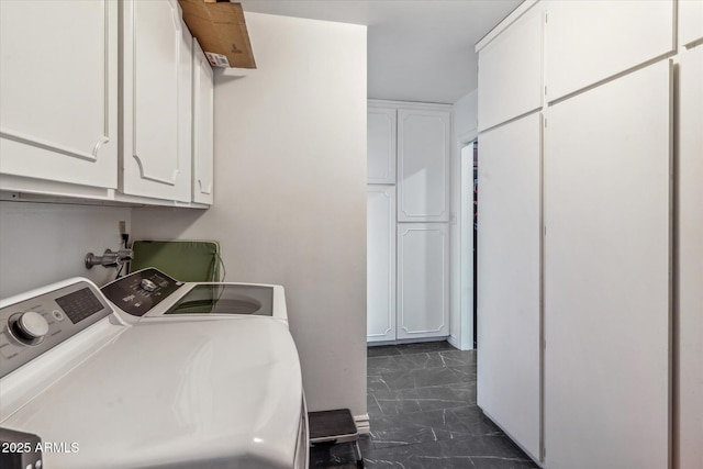 clothes washing area with cabinets and washing machine and clothes dryer