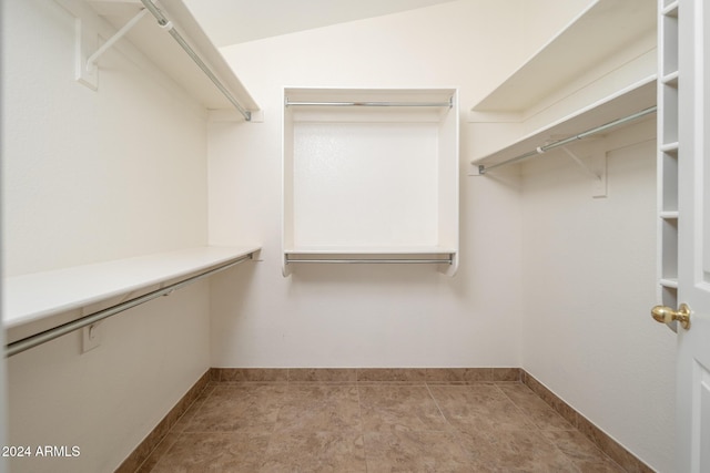 spacious closet featuring light tile patterned flooring and vaulted ceiling