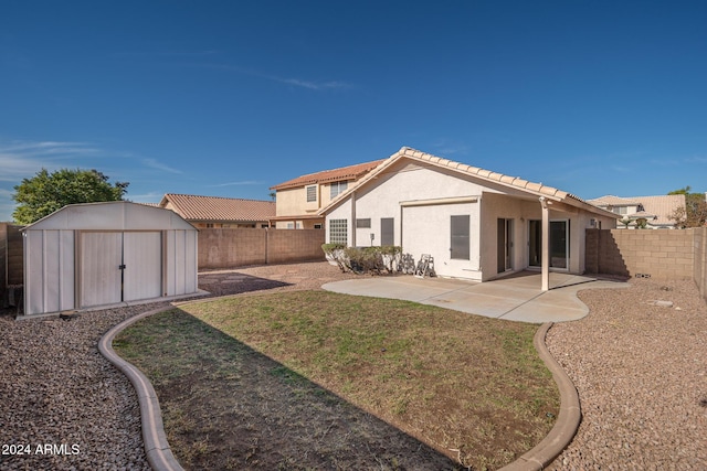 rear view of property featuring a shed, a patio area, and a lawn