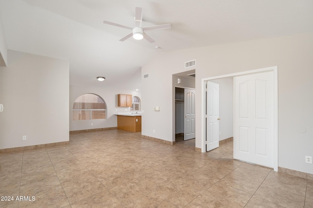 unfurnished living room with ceiling fan, light tile patterned flooring, and vaulted ceiling