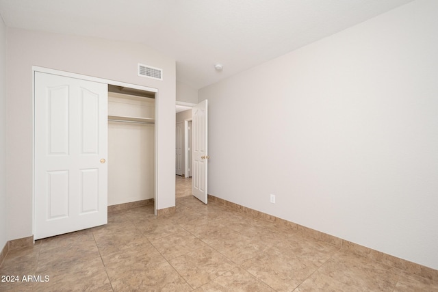 unfurnished bedroom with lofted ceiling and a closet