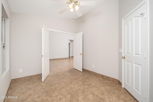 unfurnished bedroom with ceiling fan, light tile patterned floors, and lofted ceiling