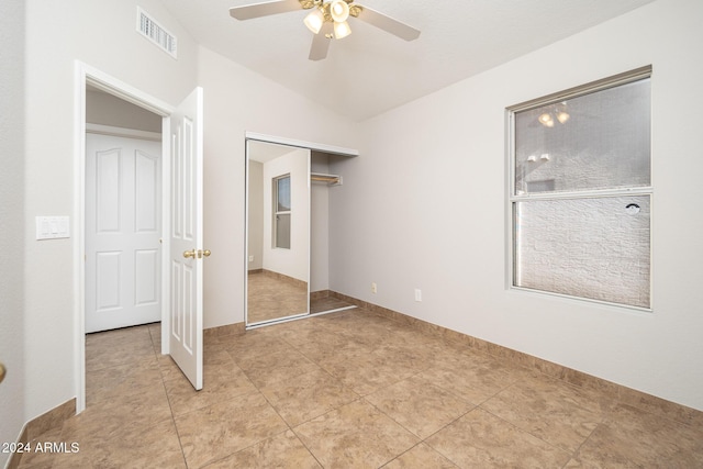 unfurnished bedroom featuring light tile patterned floors, vaulted ceiling, a closet, and ceiling fan