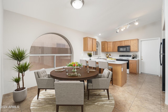 kitchen with sink, kitchen peninsula, vaulted ceiling, light tile patterned floors, and black appliances