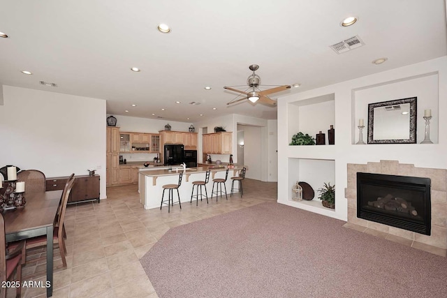 tiled living room featuring ceiling fan and a tiled fireplace