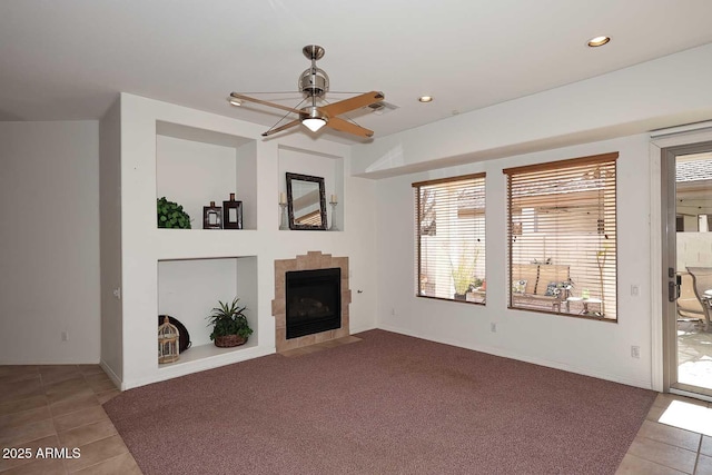 unfurnished living room with a tile fireplace, a wealth of natural light, tile patterned flooring, and ceiling fan