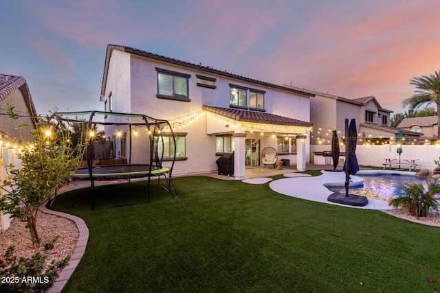 1429 E Lowell Ave, Gilbert, AZ 85295 - back of property at dusk with a trampoline, a patio, and stucco siding