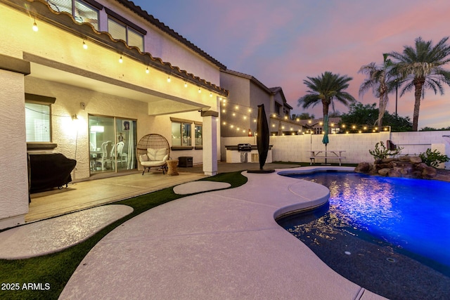 1429 E Lowell Ave, Gilbert, AZ 85295 - pool at dusk featuring a fenced backyard, a patio, an outdoor kitchen, and grilling area