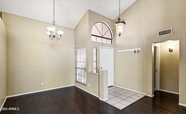 foyer with hardwood / wood-style floors, a textured ceiling, high vaulted ceiling, and an inviting chandelier