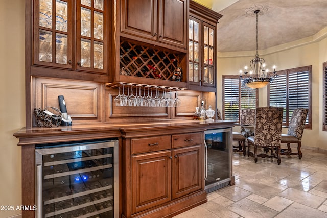 bar with pendant lighting, beverage cooler, and a notable chandelier