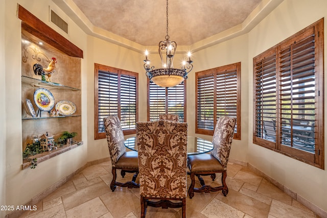 dining space with a chandelier and a raised ceiling