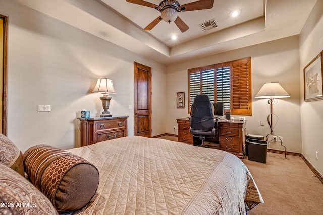 carpeted bedroom with ceiling fan and a tray ceiling