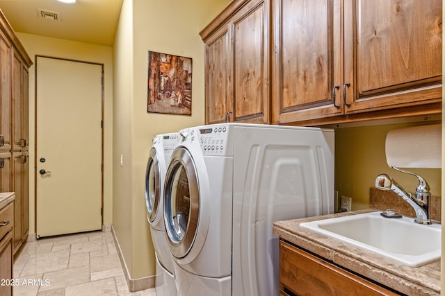 clothes washing area featuring cabinets, washer and clothes dryer, and sink