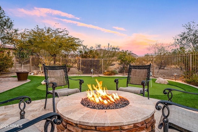 patio terrace at dusk featuring a yard and an outdoor fire pit