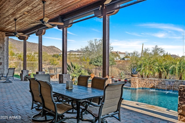 view of patio / terrace featuring pool water feature, ceiling fan, a fenced in pool, and a mountain view