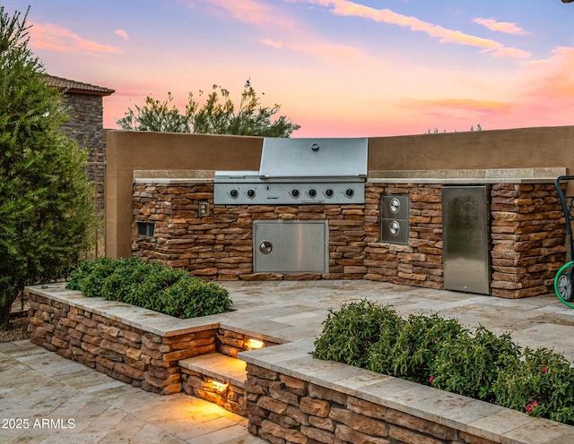 patio terrace at dusk with an outdoor kitchen and grilling area