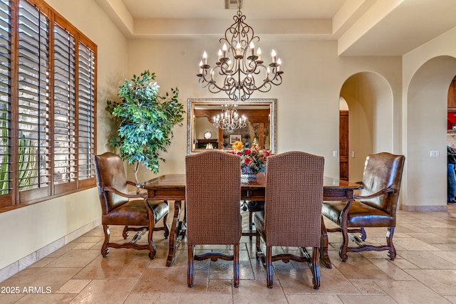 dining space with an inviting chandelier and a raised ceiling