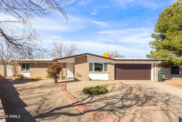 mid-century inspired home featuring a garage, concrete driveway, brick siding, and a chimney