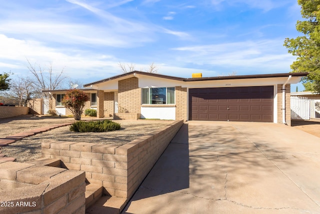 view of front facade with driveway, brick siding, an attached garage, and fence