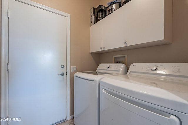 laundry area with washer and dryer, light tile patterned floors, and cabinets