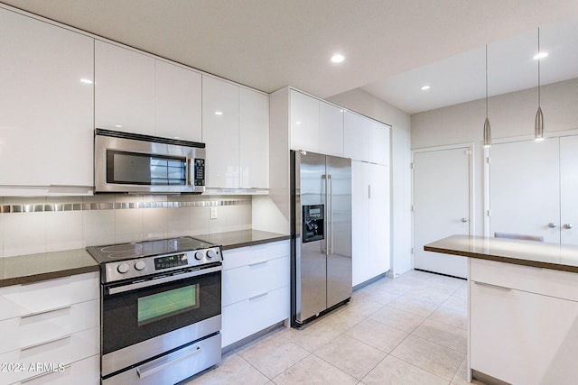 kitchen featuring appliances with stainless steel finishes, dark countertops, white cabinets, and backsplash