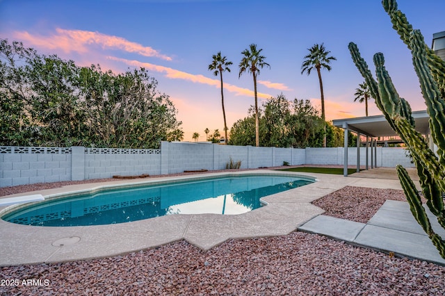 pool at dusk with a patio area