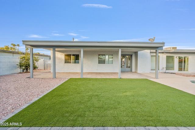 rear view of house featuring french doors, a patio, and a lawn