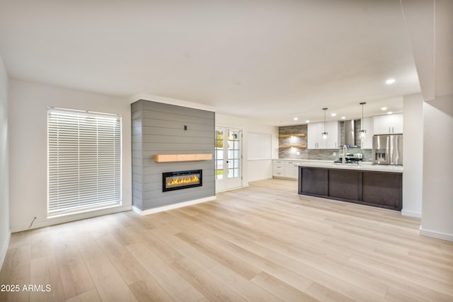 kitchen with stainless steel fridge, pendant lighting, light hardwood / wood-style floors, decorative backsplash, and white cabinets