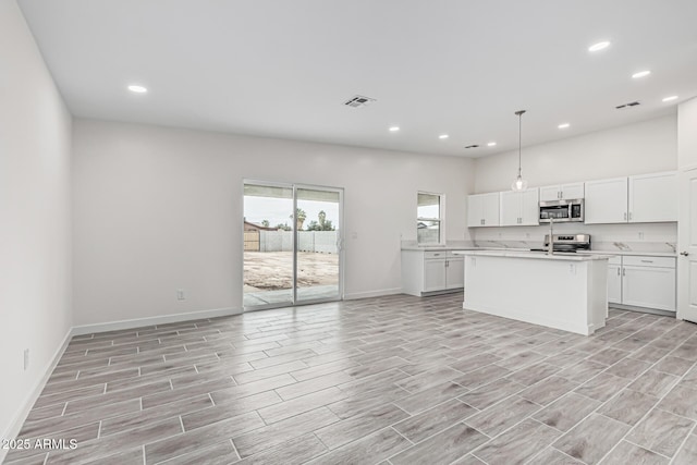 kitchen with stainless steel appliances, open floor plan, visible vents, baseboards, and light countertops