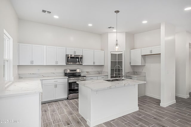 kitchen with white cabinets, stainless steel appliances, a sink, visible vents, and wood tiled floor