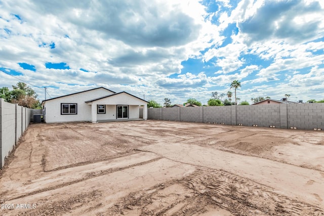 rear view of house with a fenced backyard and stucco siding