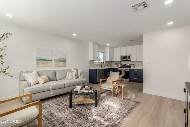 living room with light hardwood / wood-style floors and sink