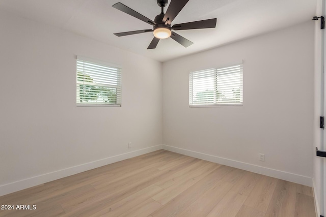 spare room featuring light wood-type flooring, ceiling fan, and a healthy amount of sunlight