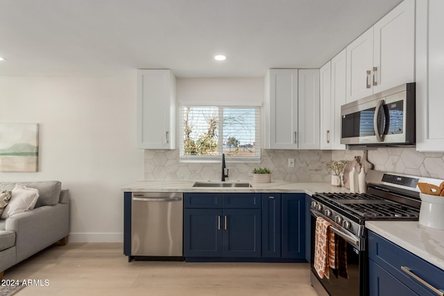 kitchen featuring white cabinets, sink, blue cabinetry, and appliances with stainless steel finishes