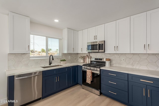 kitchen featuring sink, light wood-type flooring, blue cabinetry, white cabinetry, and stainless steel appliances