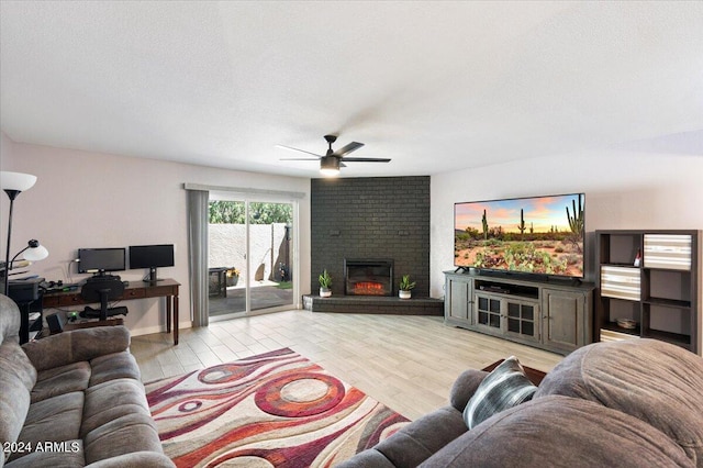 living room featuring light hardwood / wood-style flooring, ceiling fan, a textured ceiling, and a brick fireplace