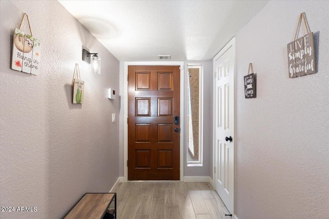 doorway featuring light hardwood / wood-style floors and a textured ceiling