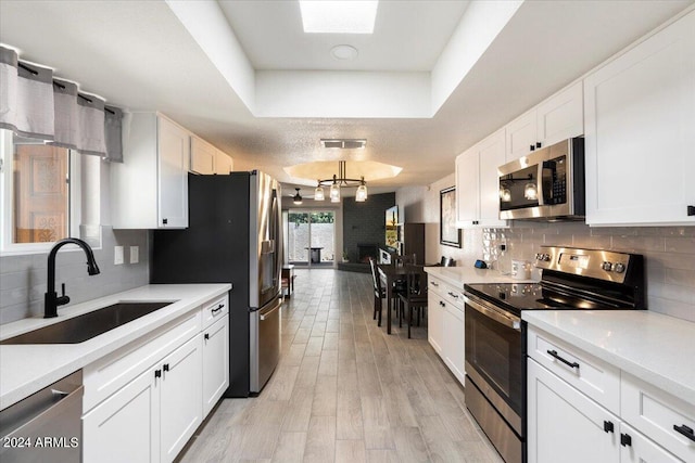 kitchen with light wood-type flooring, white cabinets, stainless steel appliances, and sink