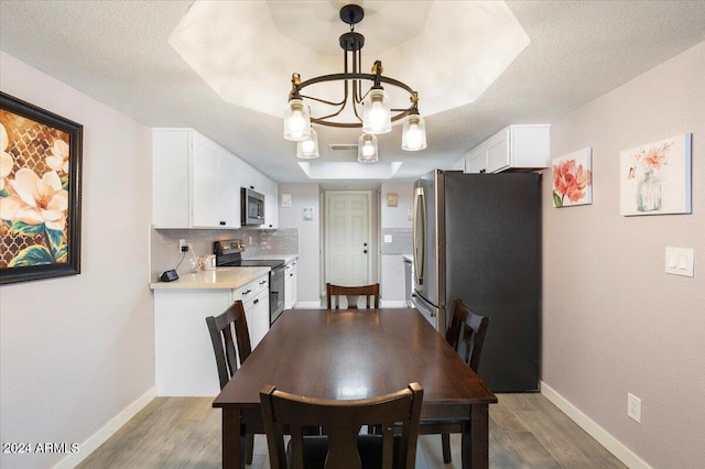 dining space with a raised ceiling, dark hardwood / wood-style flooring, a chandelier, and a textured ceiling