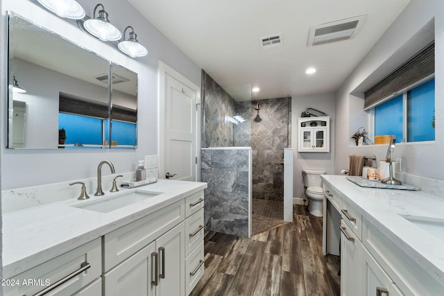 bathroom featuring a tile shower, vanity, hardwood / wood-style flooring, and toilet