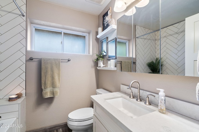 bathroom featuring a tile shower, vanity, and toilet