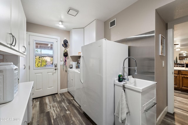 clothes washing area with washer and clothes dryer, dark hardwood / wood-style floors, ceiling fan, and cabinets