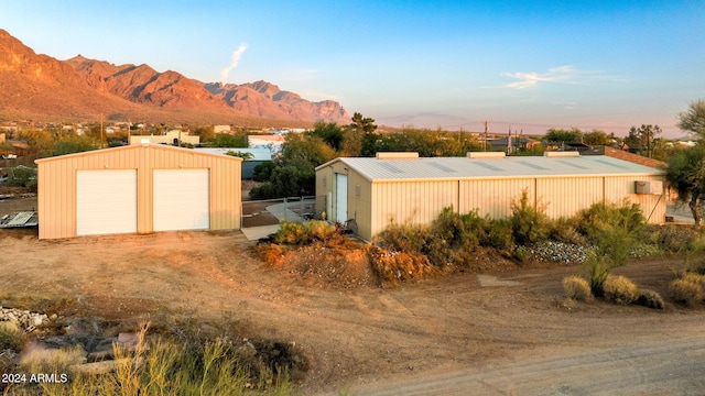 yard at dusk with a mountain view, an outbuilding, and a garage