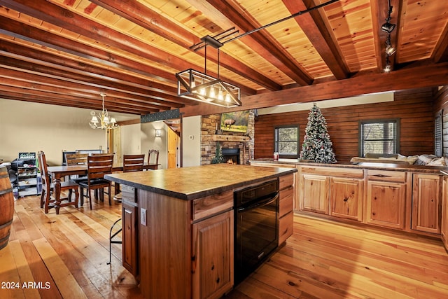 kitchen featuring light wood-type flooring, a center island, pendant lighting, wood ceiling, and a kitchen breakfast bar