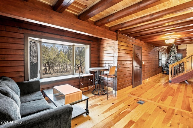 living room with beamed ceiling, light hardwood / wood-style flooring, wood ceiling, and wooden walls