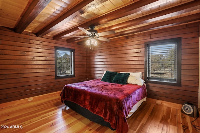 bedroom featuring beam ceiling, light wood-type flooring, wood walls, and wooden ceiling