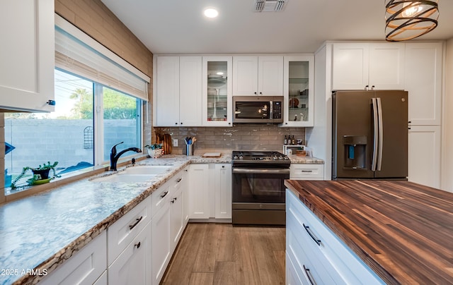 7226 E Virginia Ave, Scottsdale, AZ 85257 - kitchen featuring appliances with stainless steel finishes, wooden counters, a sink, backsplash, and white cabinetry